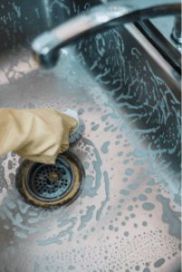 cleaning a sink wearing gloves