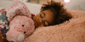 A little girl sleeping in her bed, hugging a stuffed animal