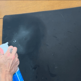 Spraying EarthSential mouse pad restorative cleaner, how to clean a mouse pad